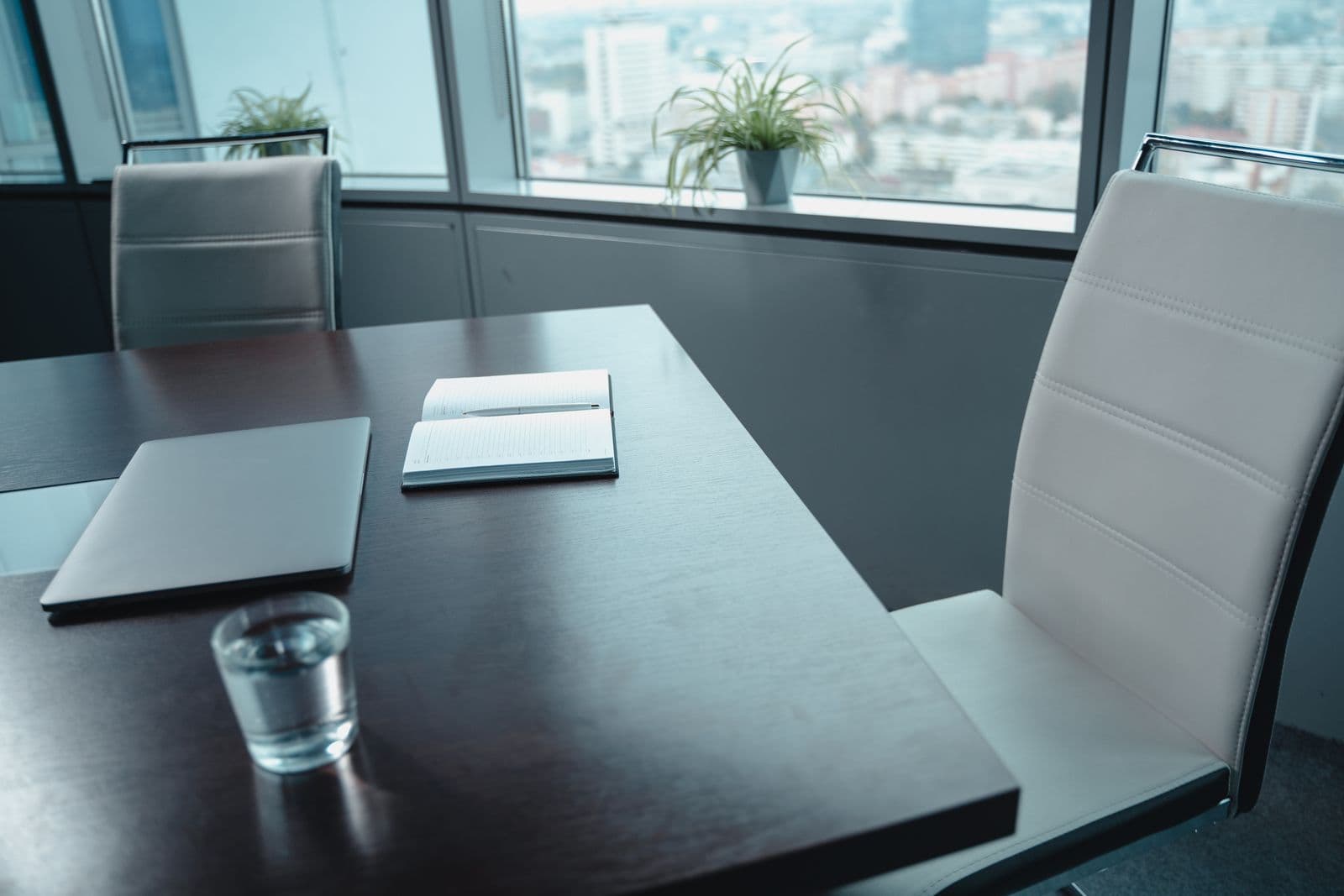 Empty modern conference room with a laptop, notebook, and city view